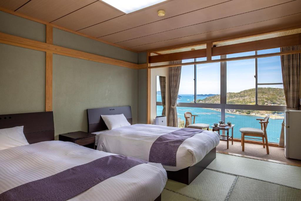 deux lits dans une chambre avec vue sur l'océan dans l'établissement Ama no Shima, à Toba