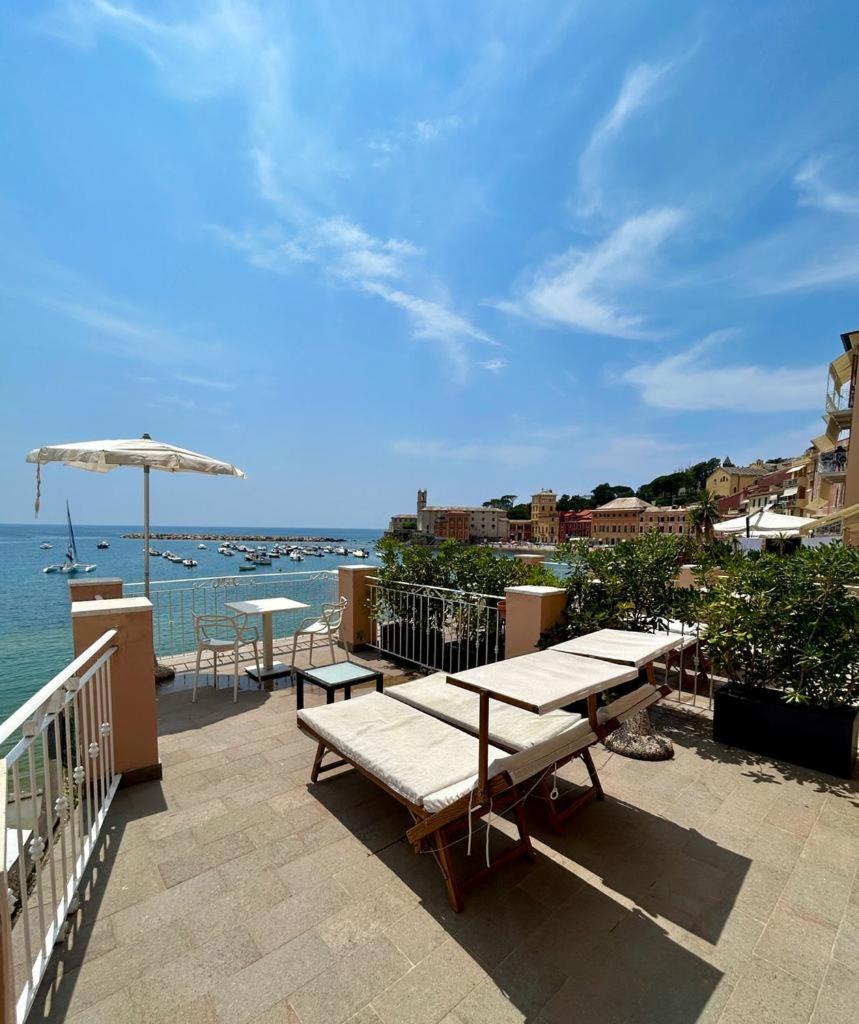 un patio avec des tables et un parasol et l'océan dans l'établissement Hotel Miramare & Spa, à Sestri Levante