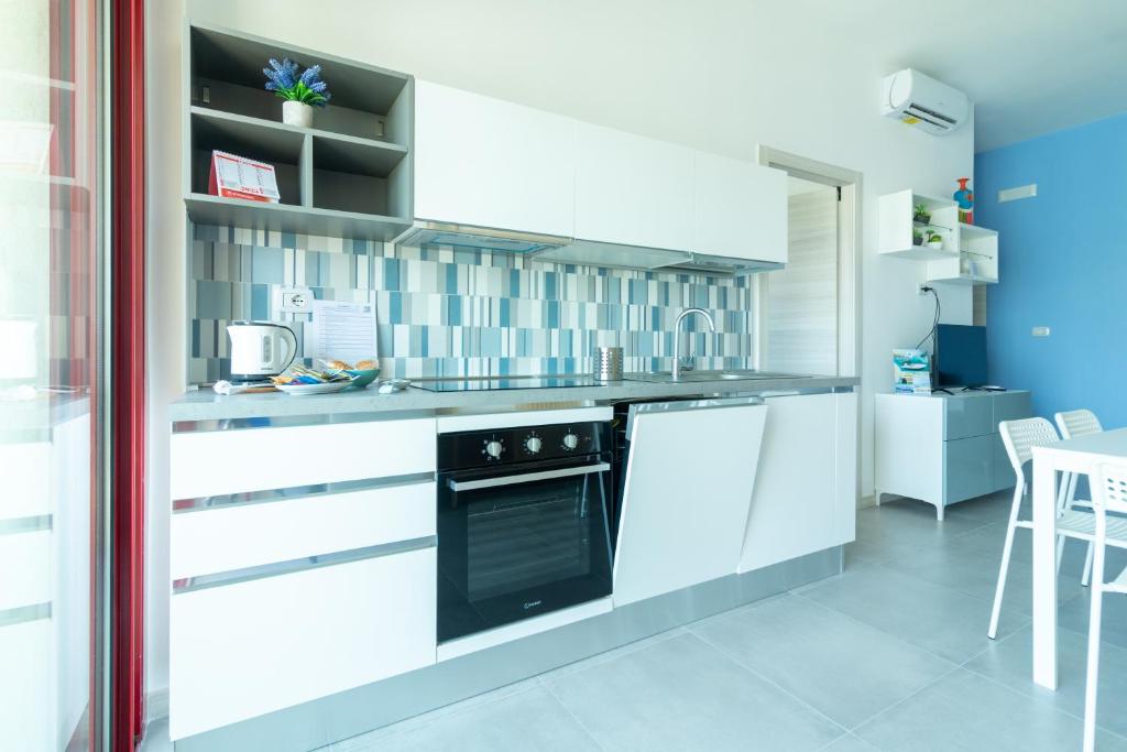 une cuisine avec des armoires blanches et une cuisinière dans l'établissement Appartamenti Craulo, à Otrante 70 autres photos