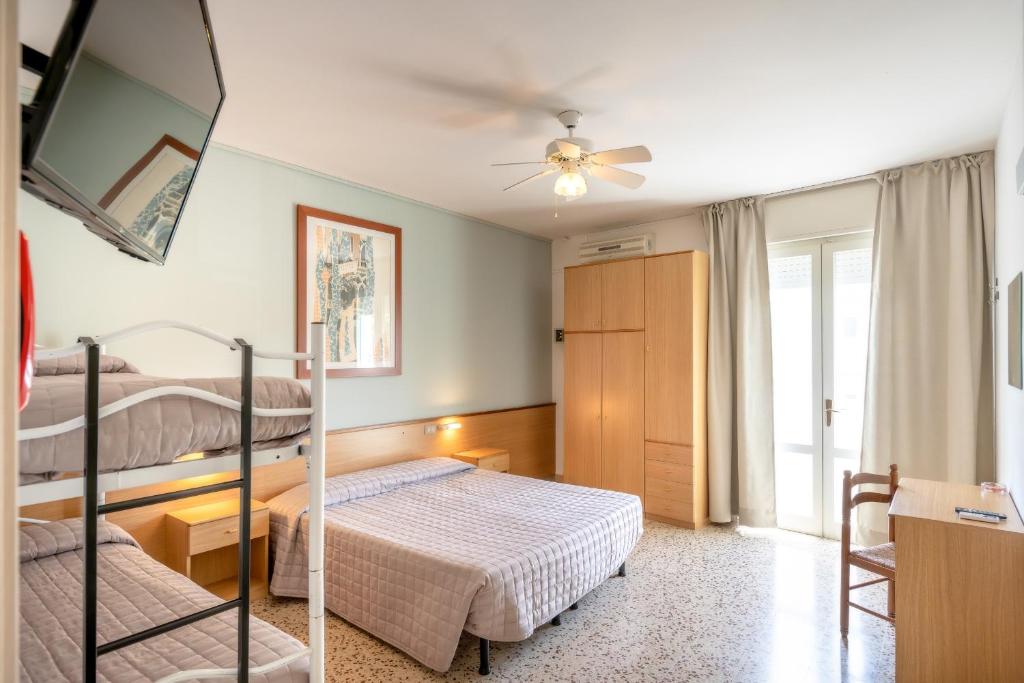 une chambre avec deux lits et un ventilateur de plafond dans l'établissement Hotel Itta, à Caorle