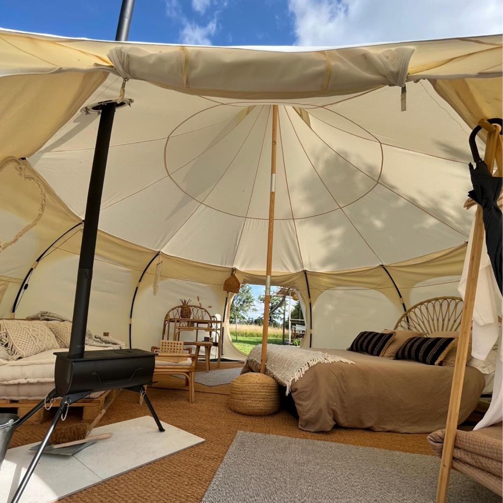 une tente avec un lit et une chaise dans une chambre dans l'établissement La Prairie Étoilée Luxury Glamping - Adults Only, à Crozon-sur-Vauvre