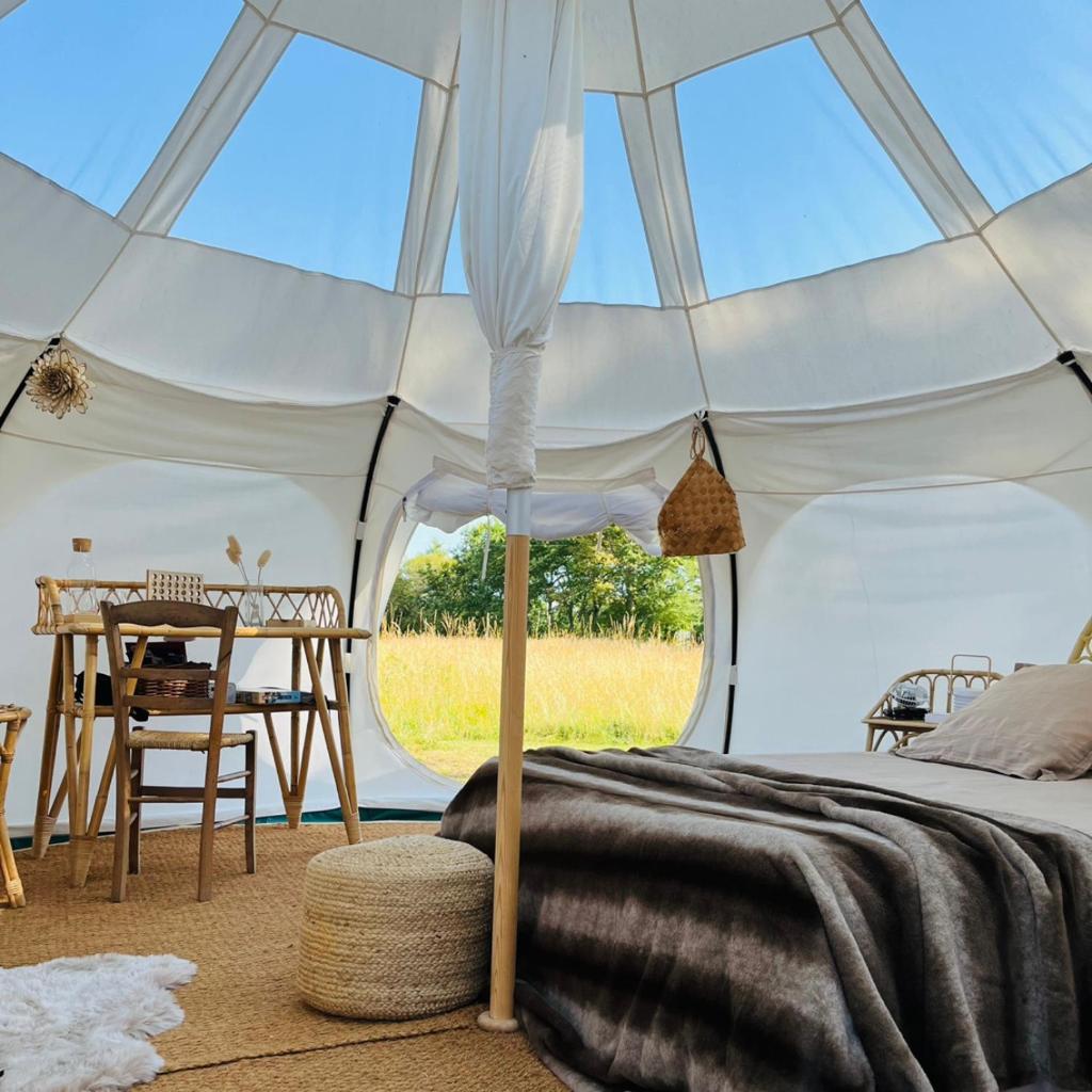 une tente blanche avec un lit et une table dans l'établissement La Prairie Étoilée Luxury Glamping - Adults Only, à Crozon-sur-Vauvre