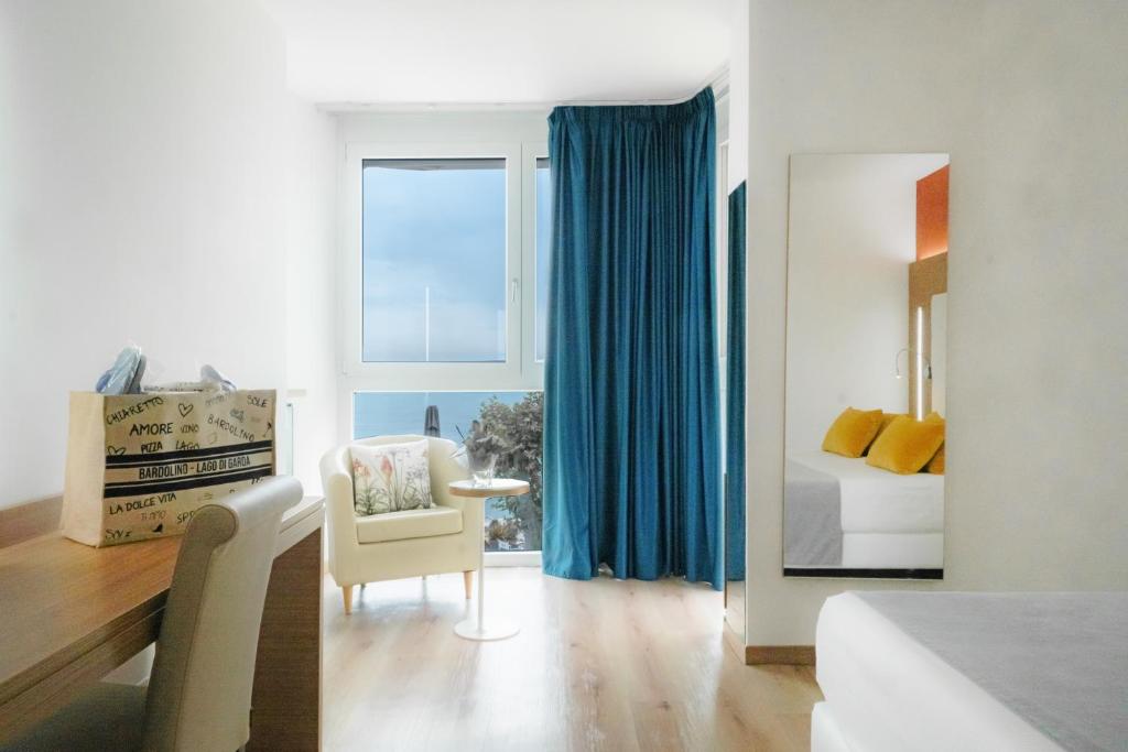 une chambre avec un lit, une chaise et une fenêtre dans l'établissement Kriss Internazionale Hotel, à Bardolino