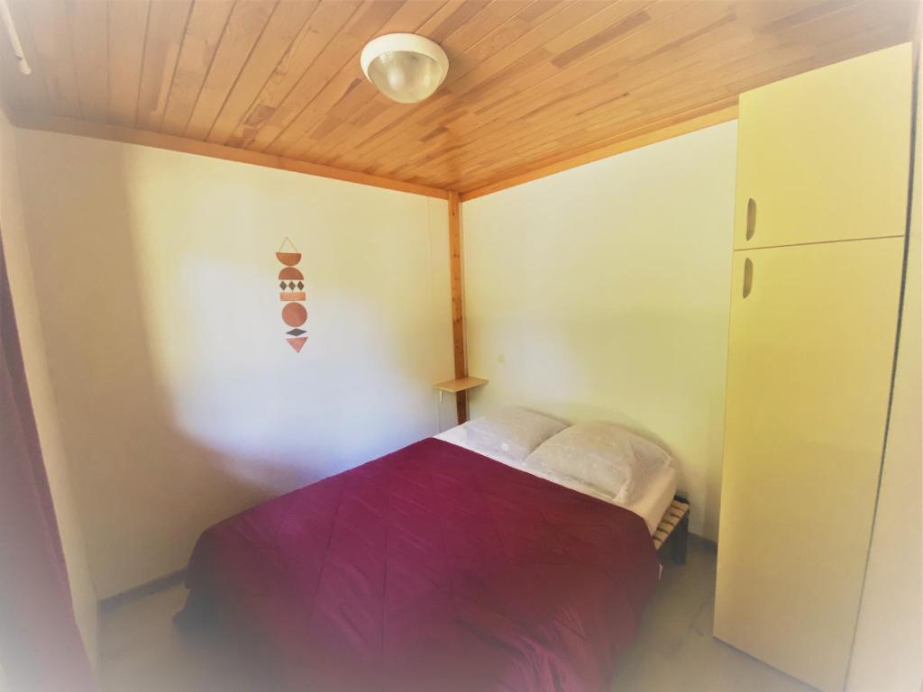 une petite chambre avec un lit violet dans le coin dans l'établissement Camping familial les chalets d'Uza, à Uza