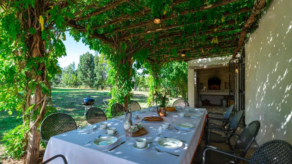 une table avec des assiettes de nourriture assise sous une pergola dans l'établissement LA CASA NEI VIGNETI 10, Emma Villas, à Catignano