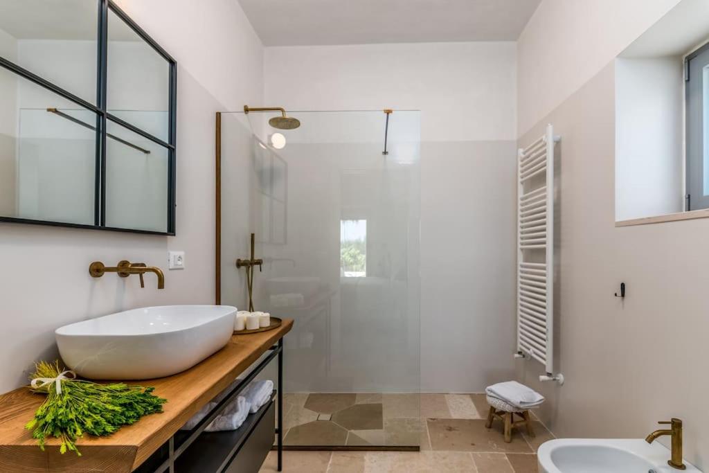 La salle de bains est pourvue d'un grand lavabo blanc et d'une baignoire. dans l'établissement LaCorte di Ninetta., à Ostuni