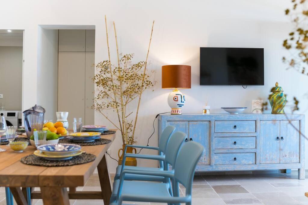 une salle à manger avec une table, des chaises bleues et une télévision dans l'établissement LaCorte di Ninetta., à Ostuni