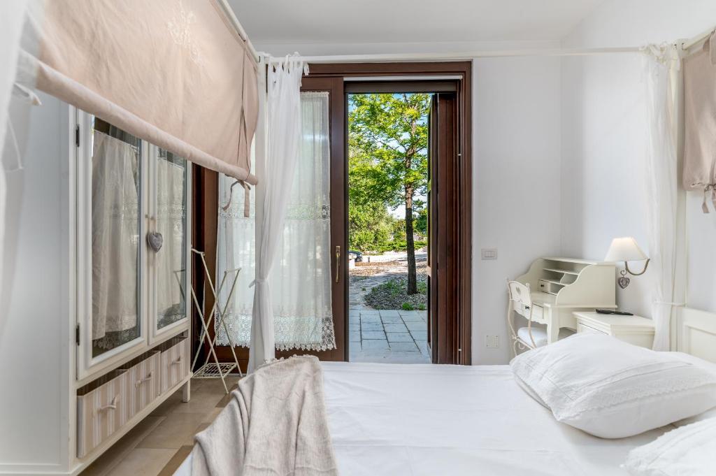- une chambre blanche avec un lit et une porte coulissante en verre dans l'établissement Trulli Ericla Luxury, à Castellana Grotte