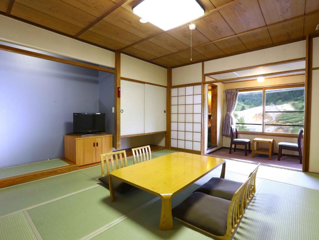 une pièce avec une table, des chaises et une télévision dans l'établissement Manza Onsen Nisshinkan, à Tsumagoi