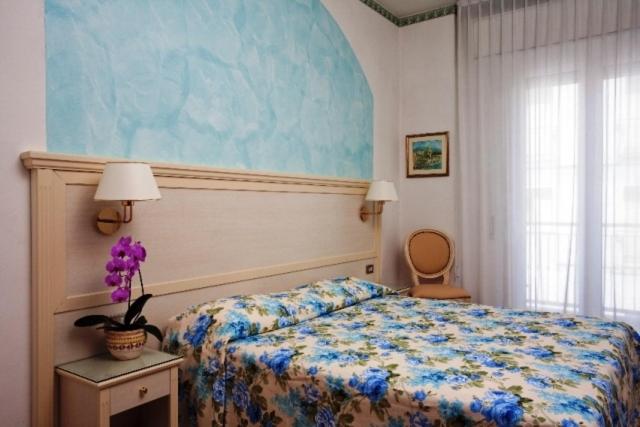 - une chambre avec un lit orné d'une peinture bleue sur le mur dans l'établissement Hotel Arcade, à Rimini