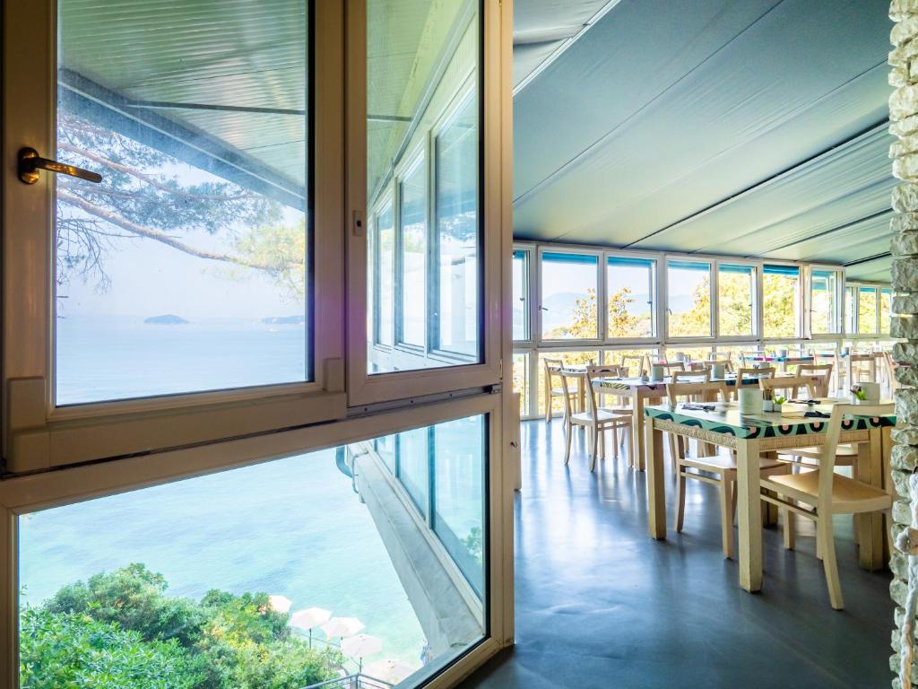 une salle à manger avec une table, des chaises et des fenêtres dans l'établissement Hotel Il Nido, à Tellaro