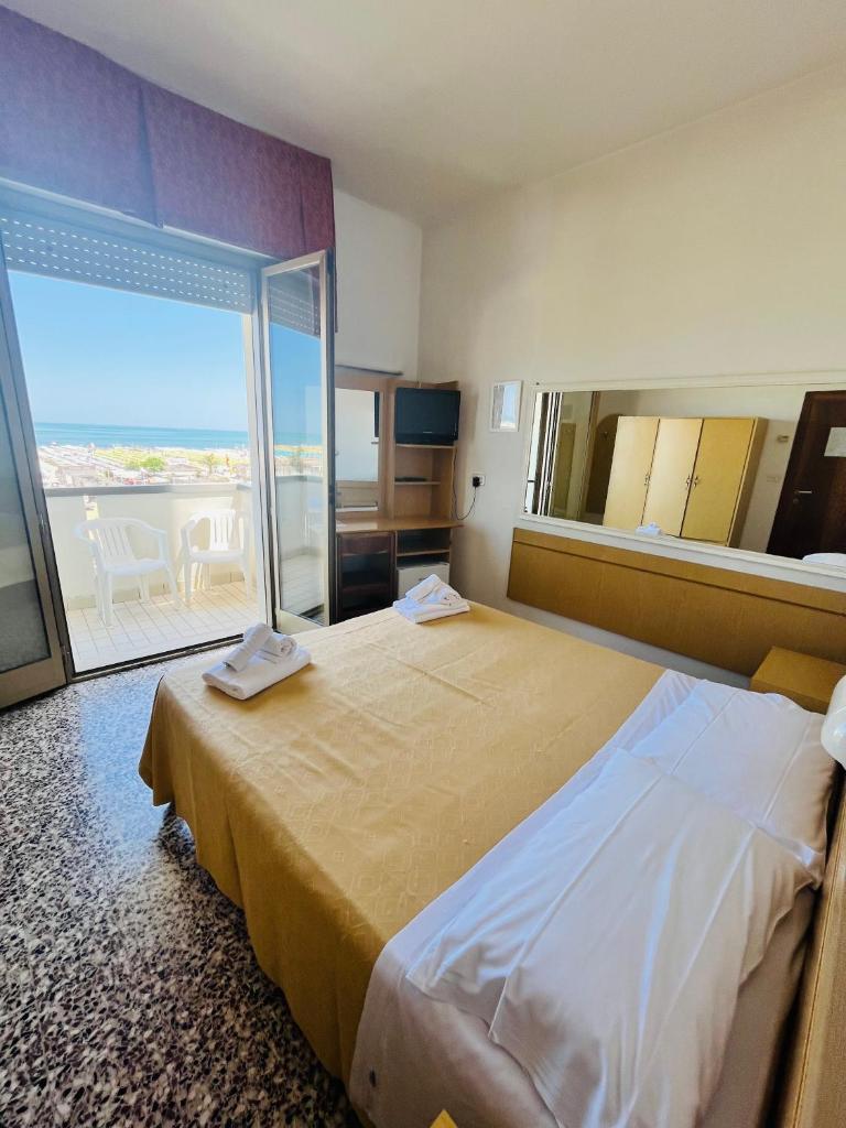 une chambre d'hôtel avec un grand lit et une grande fenêtre dans l'établissement Hotel Columbia Frontemare, à Rimini