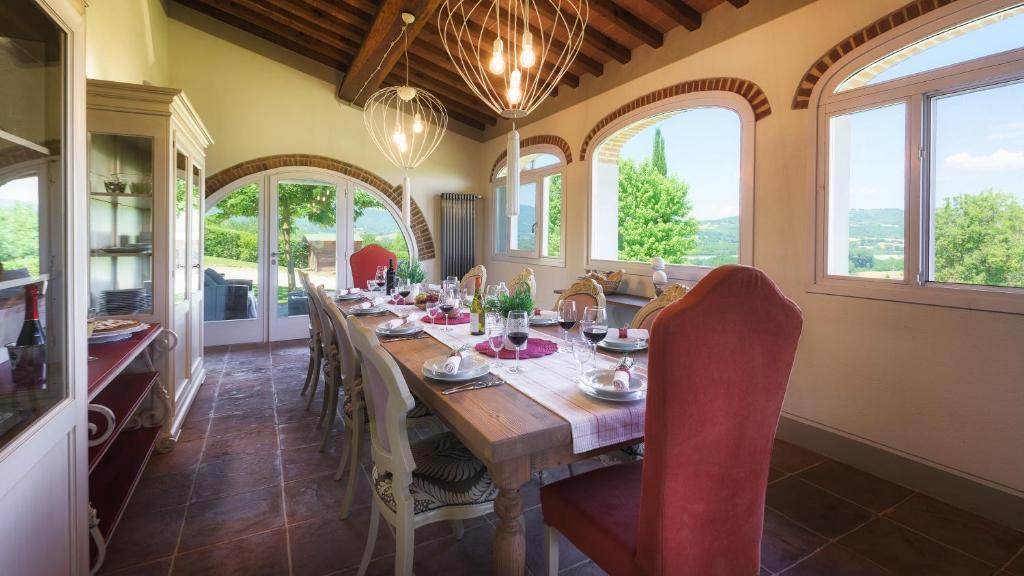 une salle à manger avec une table, des chaises et des fenêtres dans l'établissement VILLA IL MAGNIFICO 10, Emma Villas, à Reggello