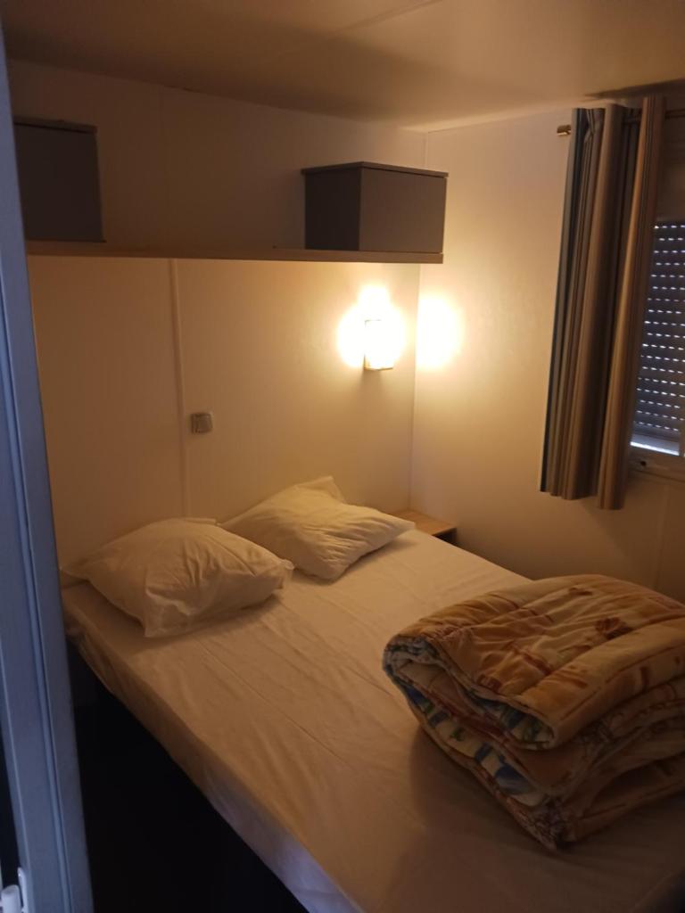 une petite chambre avec un lit avec des draps blancs et des oreillers dans l'établissement domaine de la sainte baume, à Nans-les-Pins 11 autres photos