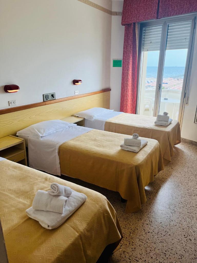 une chambre d'hôtel avec trois lits et une fenêtre dans l'établissement Hotel Columbia Frontemare, à Rimini