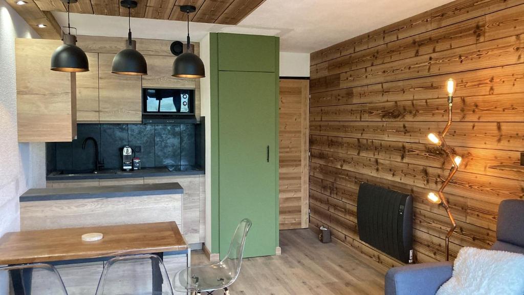 - une cuisine avec des murs en bois, une table et des chaises dans l'établissement Les Tanières de Montgenèvre - Studio Dama - neuf 4p avec terrasse vue imprenable, à Montgenèvre