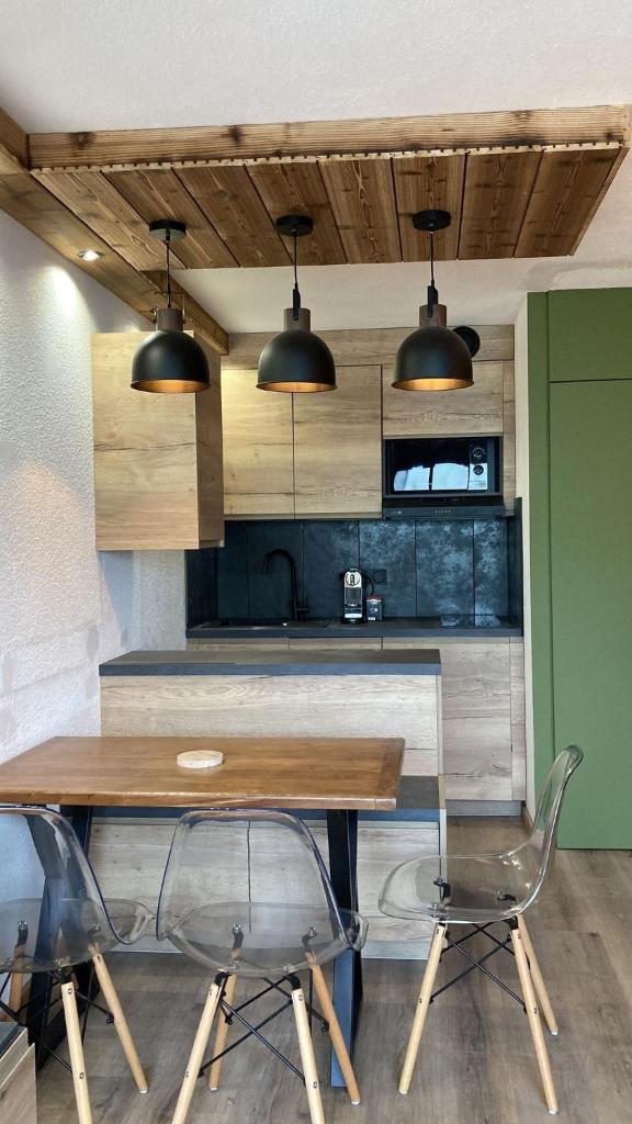 une cuisine avec une table en bois et deux chaises dans l'établissement Les Tanières de Montgenèvre - Studio Dama - neuf 4p avec terrasse vue imprenable, à Montgenèvre