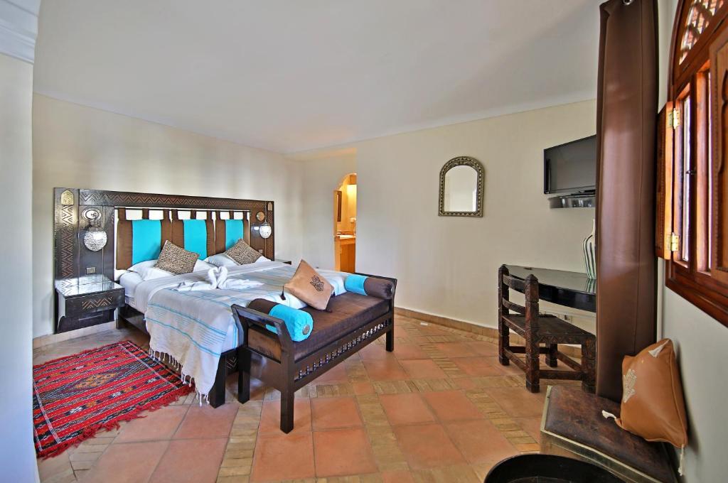 une chambre avec un grand lit et un bureau dans l'établissement Riad Dar L'Oussia & SPA, à Essaouira