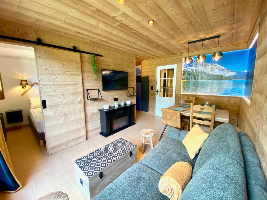 un salon avec un canapé bleu et une table dans l'établissement Appartement rénové 2 chambres vue pistes parking privatif, aux Orres