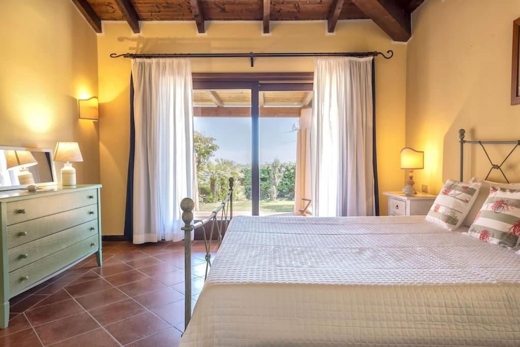 une chambre avec un grand lit et une grande fenêtre dans l'établissement ClickSardegna Villa Regina Stintino sea view with pool and garden, à Cuile Pazzoni