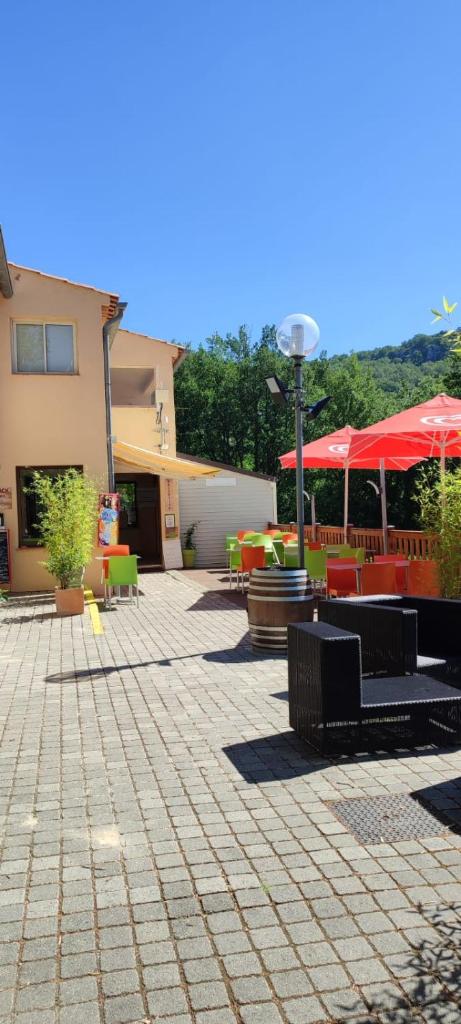 un patio avec des tables, des chaises et des parasols dans l'établissement Camping Près du Lac de Sainte Croix, à Bauduen