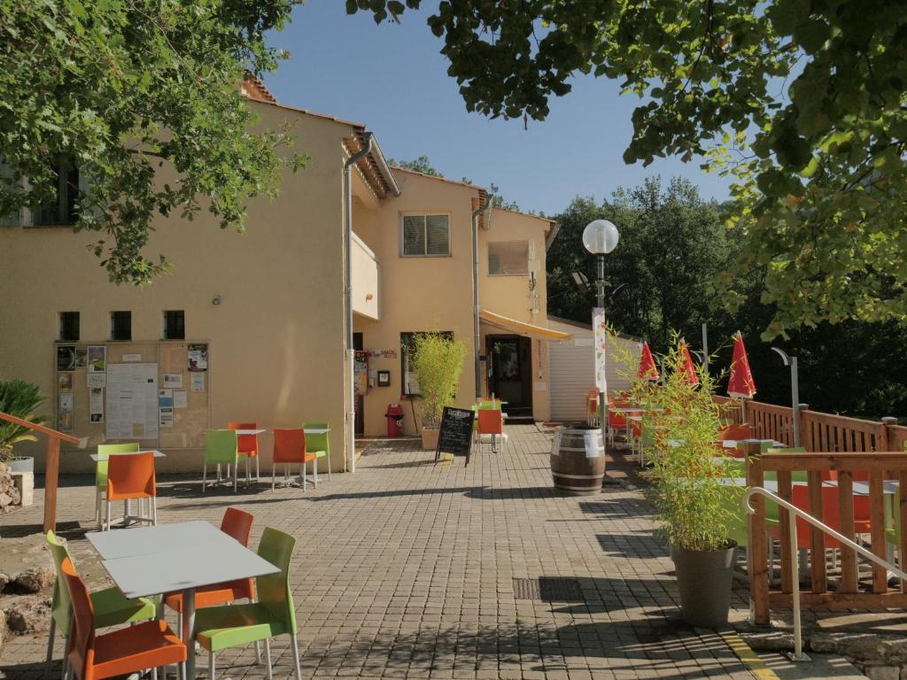 un patio avec des tables et des chaises et un bâtiment dans l'établissement Camping Près du Lac de Sainte Croix, à Bauduen
