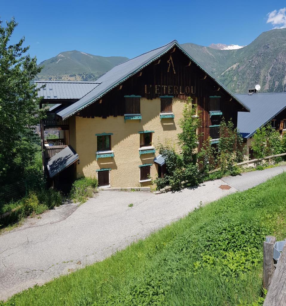 une grande grange avec une route devant elle dans l'établissement Les Balcons de l'Eterlou, à Les Deux Alpes