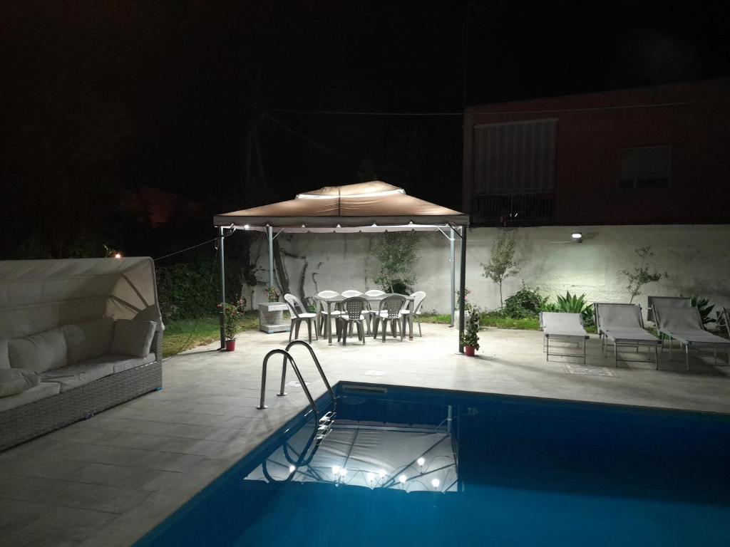 une piscine avec un parasol, une table et des chaises dans l'établissement LA PERLA BLU DI FONTANE BIANCHE, à Fontane Bianche
