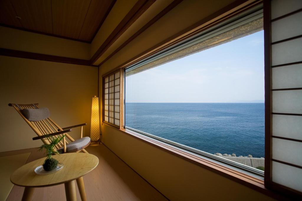 Cette chambre dispose d'une fenêtre avec une chaise et offre une vue sur l'océan. dans l'établissement Awaji International Hotel The Sunplaza, à Sumoto
