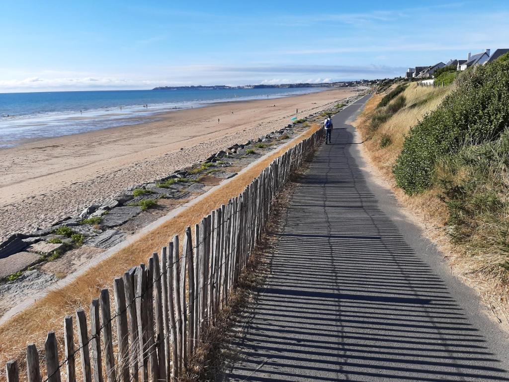 une personne se promenant sur un chemin sur une plage dans l'établissement Cottage, à Jullouville