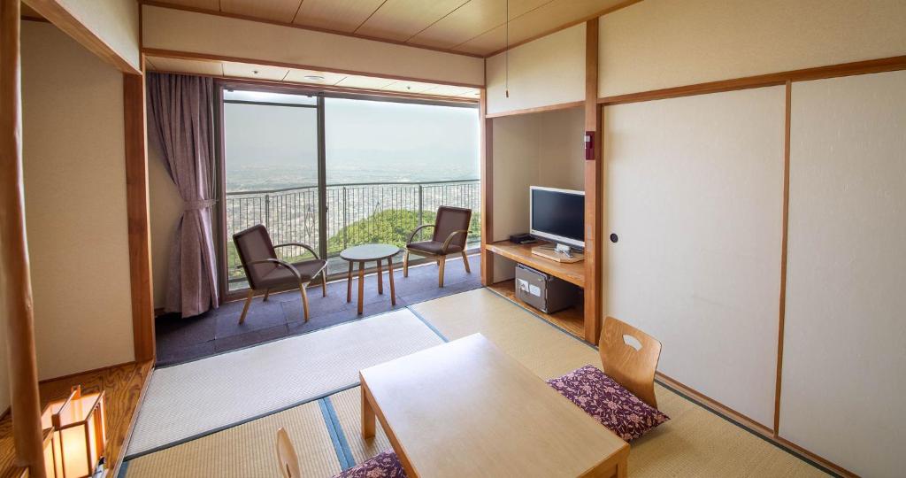 une chambre avec un balcon avec une table et des chaises dans l'établissement Bizan Kaigetsu, à Tokushima