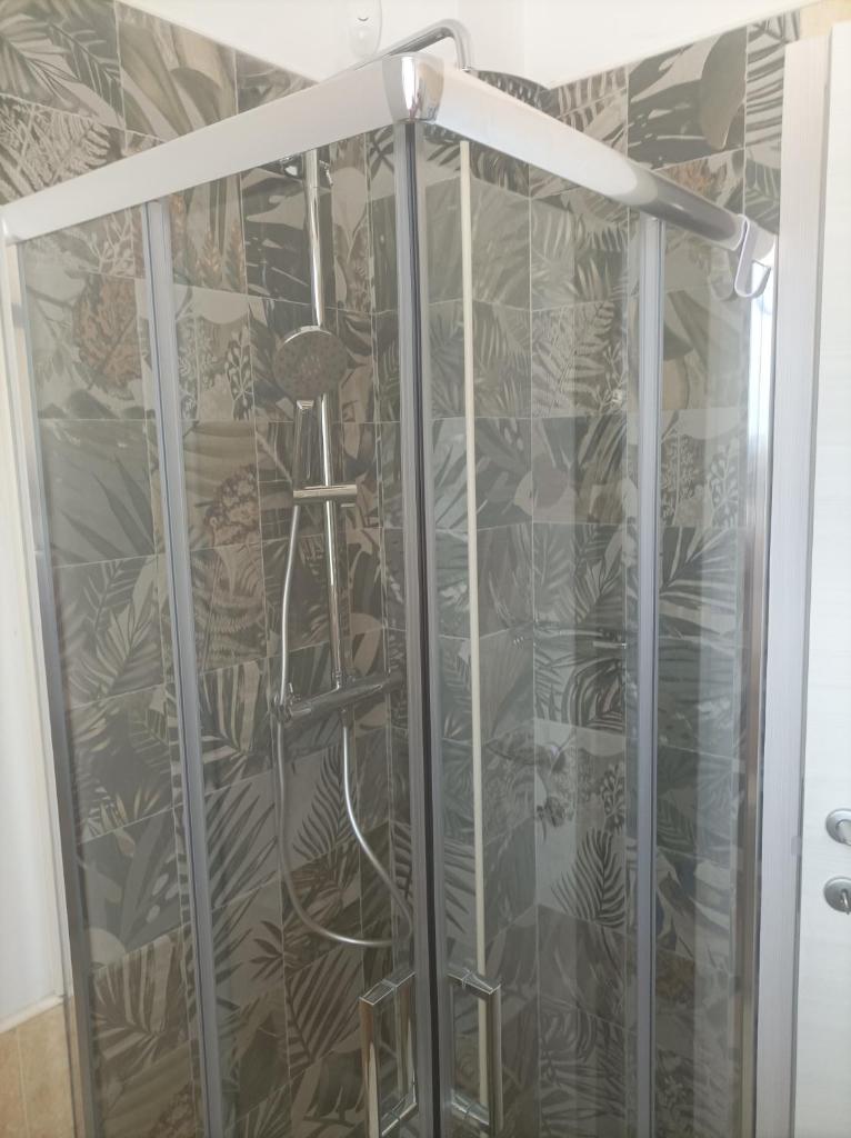 une douche avec une porte vitrée dans une salle de bain dans l'établissement Rosmat's house, à Conversano