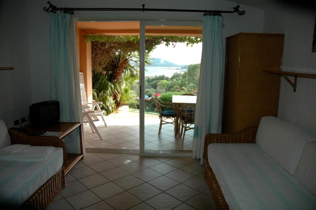 - un salon avec une porte s'ouvrant sur une terrasse dans l'établissement Residence Fenicia, à Villasimius