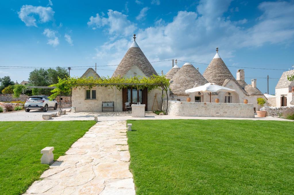 une maison aux toits de chaume avec une pelouse verte dans l'établissement Acres Itria, à Locorotondo