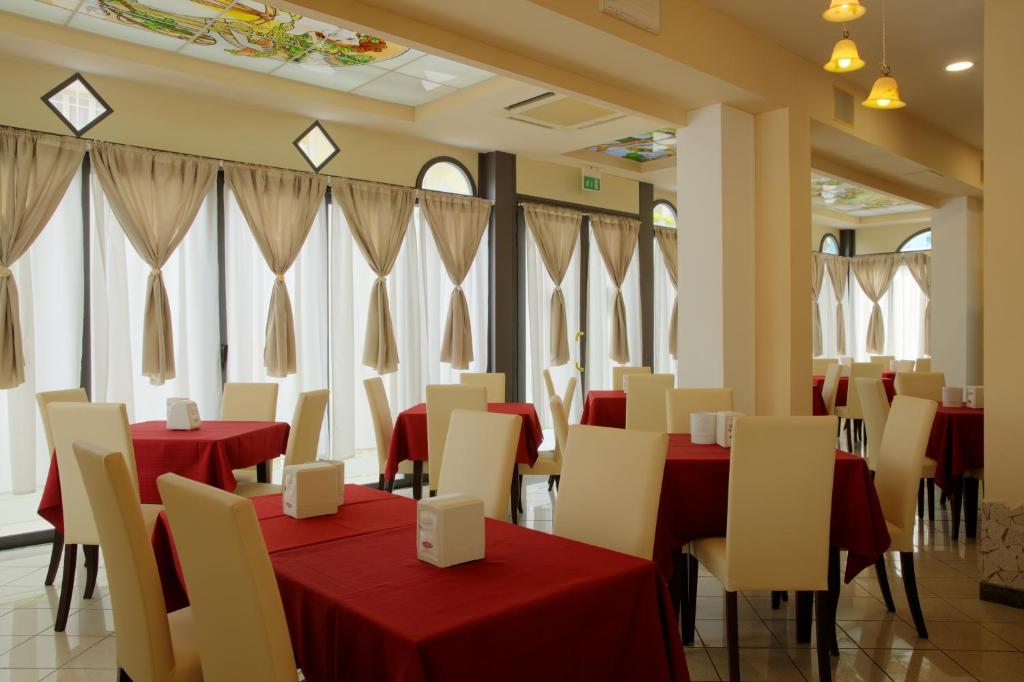 un restaurant avec des tables rouges, des chaises et des fenêtres dans l'établissement Hotel Stefan Room & Breakfast, à Gatteo a Mare