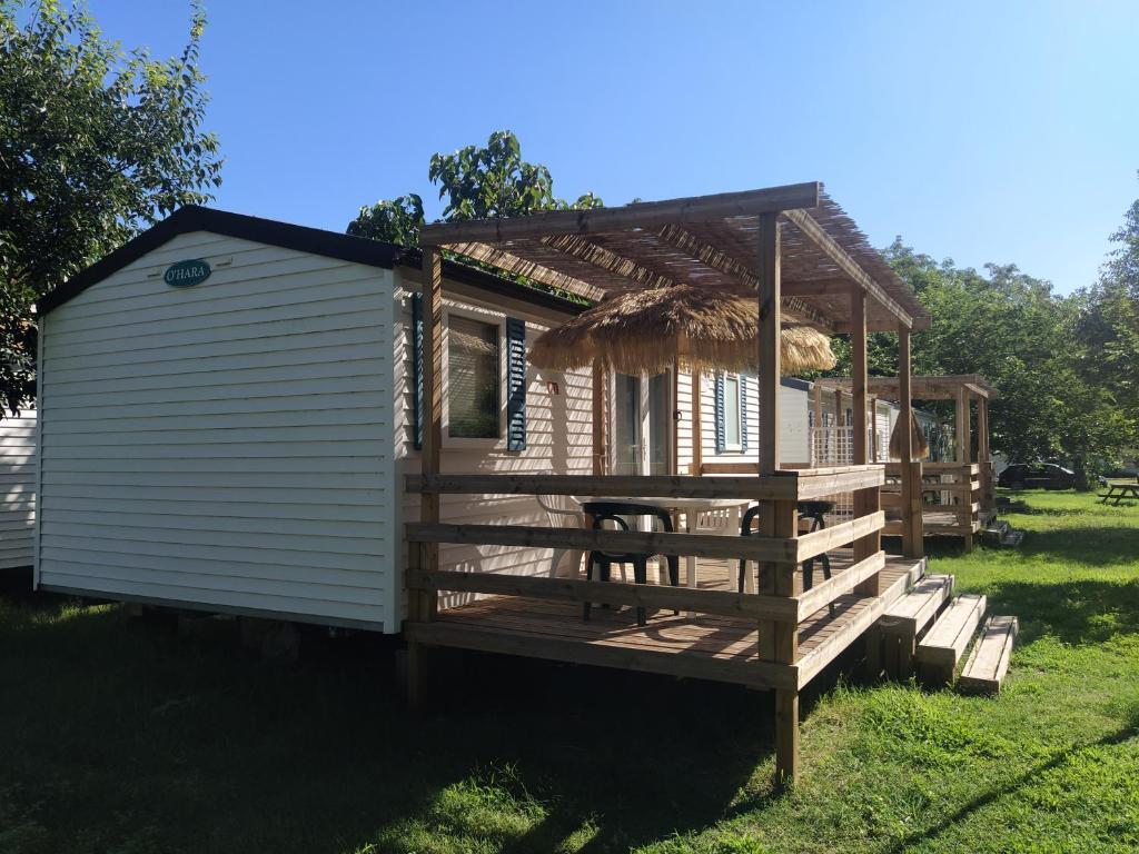 une petite maison avec un porche et une terrasse dans l'établissement Camping Le Mas Sud Ardèche, à Saint-Just