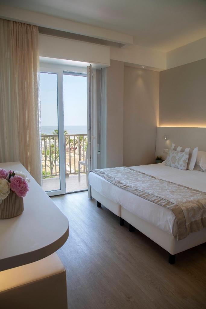 une chambre d'hôtel avec un grand lit et un balcon dans l'établissement Hotel Mon Cheri, à Riccione