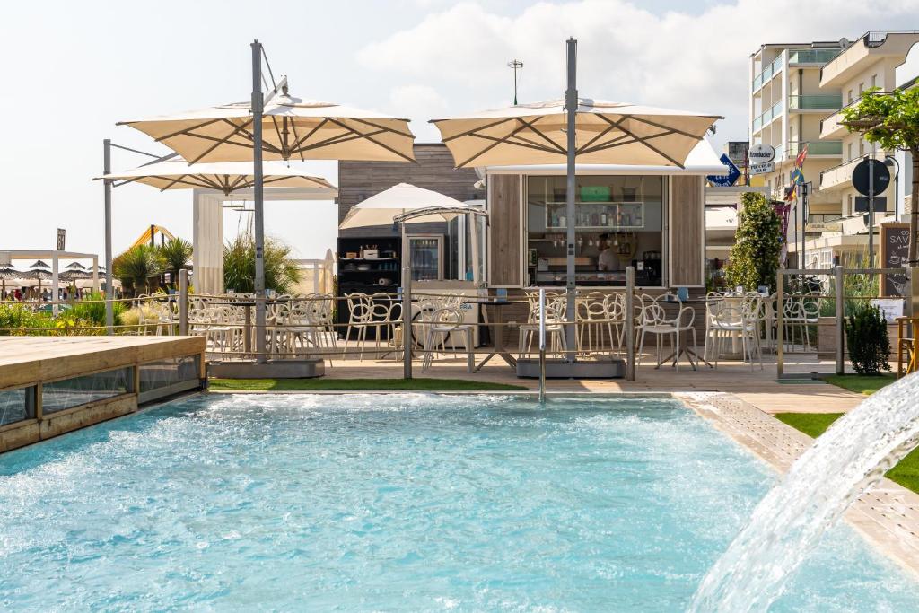 une piscine avec une fontaine en face d'un bâtiment dans l'établissement Hotel Savini, à Bellaria-Igea Marina