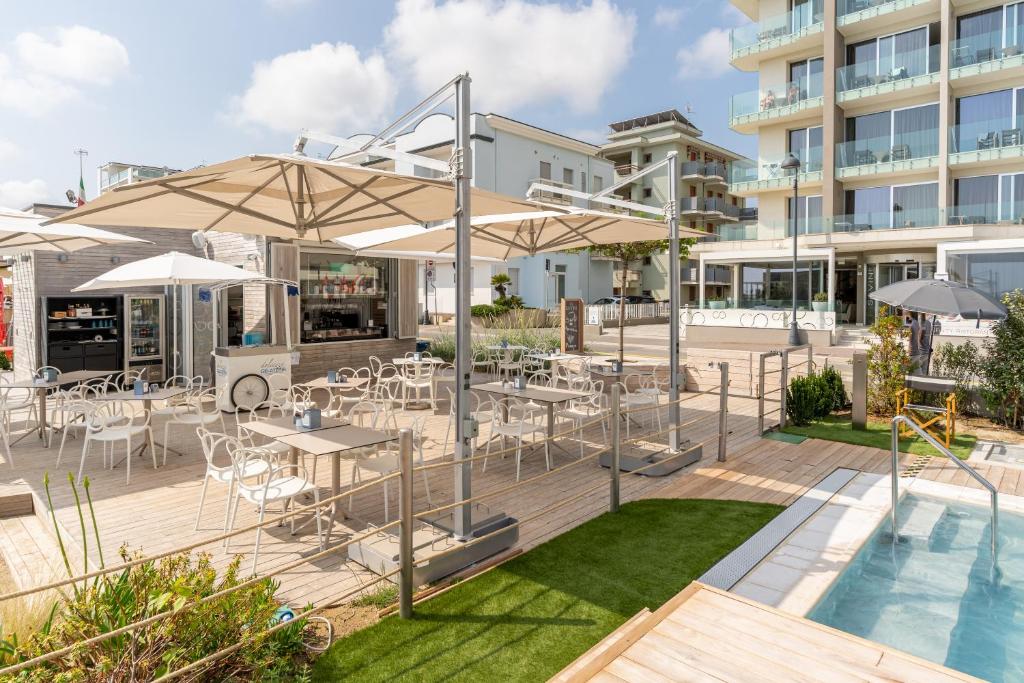 un patio avec des tables et des parasols à côté d'une piscine dans l'établissement Hotel Savini, à Bellaria-Igea Marina