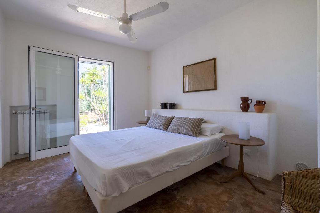 une chambre blanche avec un grand lit et une table dans l'établissement Villa Marta, à Carovigno