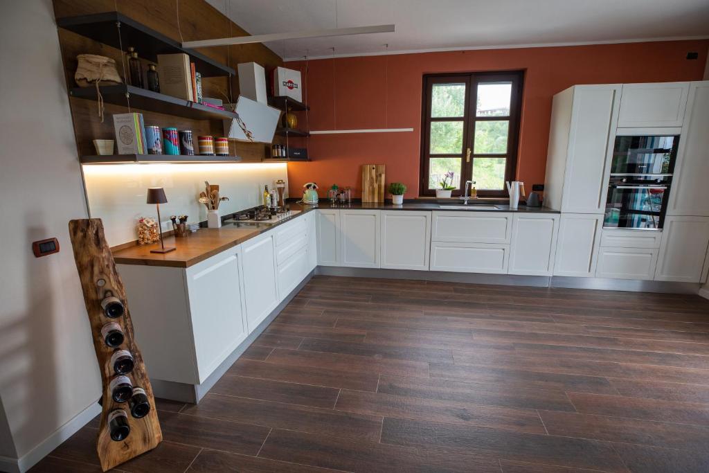 une cuisine avec des armoires blanches et un plancher en bois dans l'établissement Villa Monforte Barolo with private pool - LANGHE GATEWAY, à Monforte dʼAlba