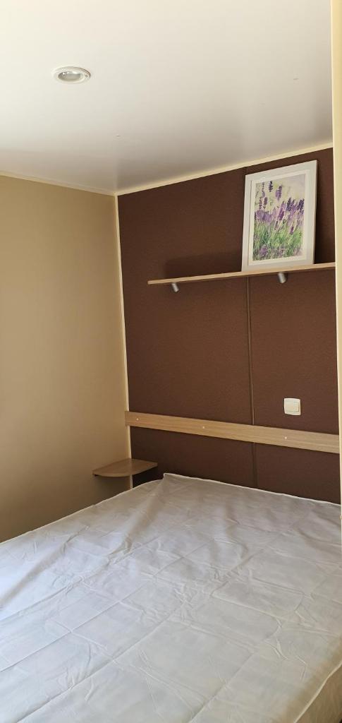 une chambre avec un lit et un tableau au mur dans l'établissement Mobil Home climatisé 6 personnes, à La Roque-dʼAnthéron