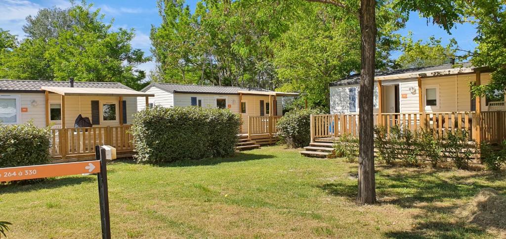une rangée de chalets avec un panneau dans la cour dans l'établissement Mobil Home climatisé 6 personnes, à La Roque-dʼAnthéron