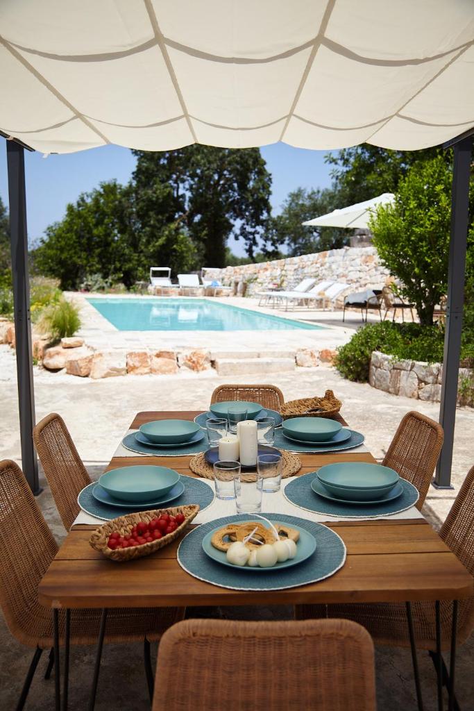 - une table en bois avec des assiettes de nourriture à côté de la piscine dans l'établissement Dimora del Carrubo, à Polignano a Mare