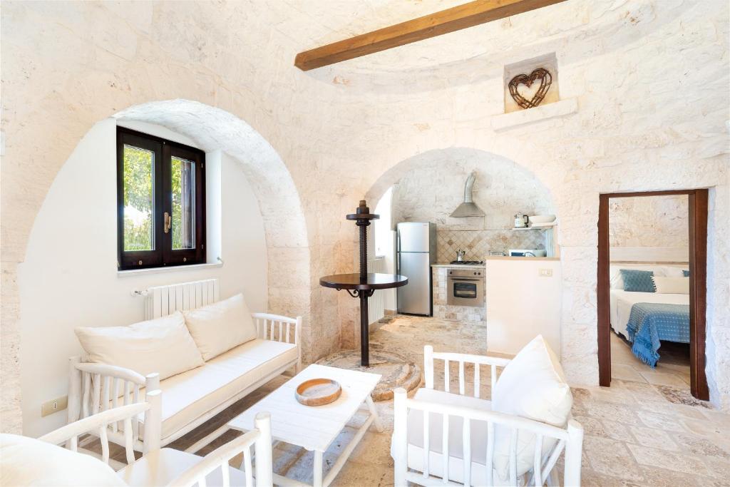 un salon avec un canapé blanc et une cuisine dans l'établissement Trullo Alba, à Martina Franca