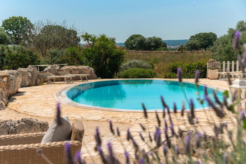 une piscine dans un jardin avec des fleurs violettes dans l'établissement Trullo Alba, à Martina Franca