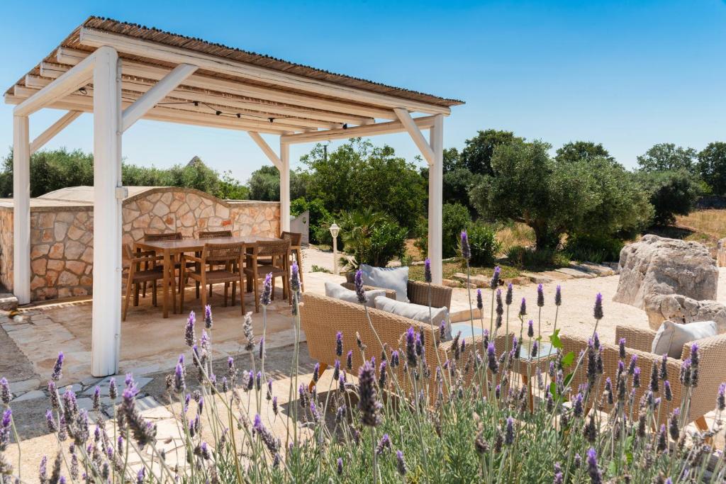 un pavillon avec une table dans un jardin avec des fleurs violettes dans l'établissement Trullo Alba, à Martina Franca