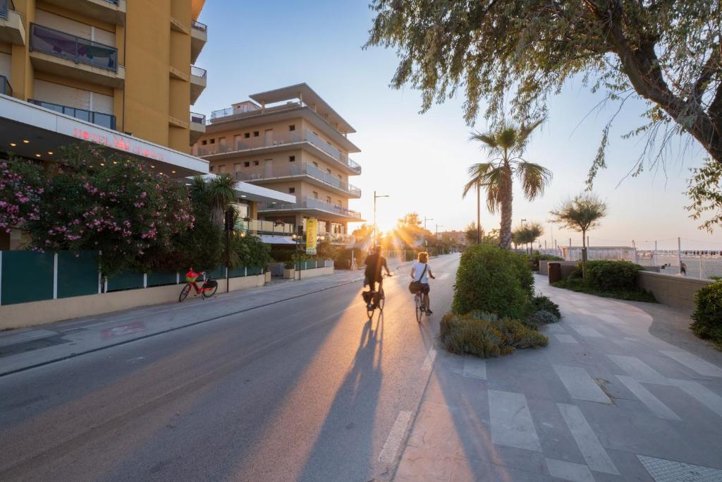 - 2 personnes en vélo dans une rue au coucher du soleil dans l'établissement Hotel Crown, à Rimini