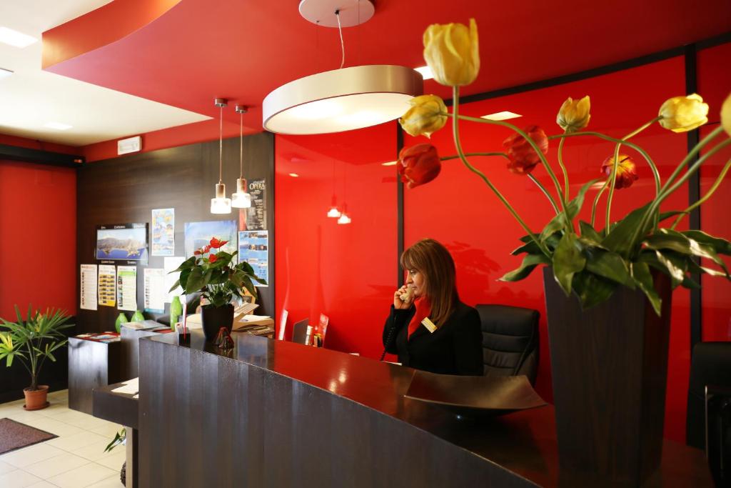 une femme assise au comptoir parlant sur un téléphone portable dans l'établissement Hotel San Giovanni, à Giardini Naxos 58 autres photos