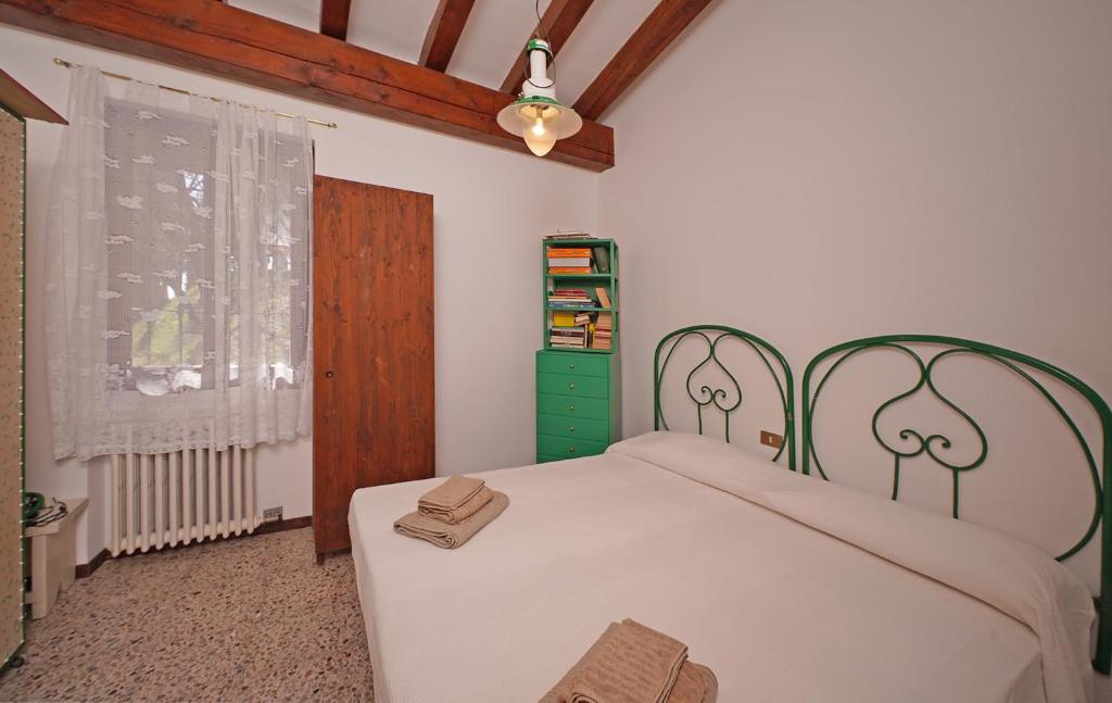 - une chambre dotée d'un lit blanc avec une tête de lit verte et une fenêtre dans l'établissement Ville in uliveto vista lago - VILLA CASALIVA, à Pulciano